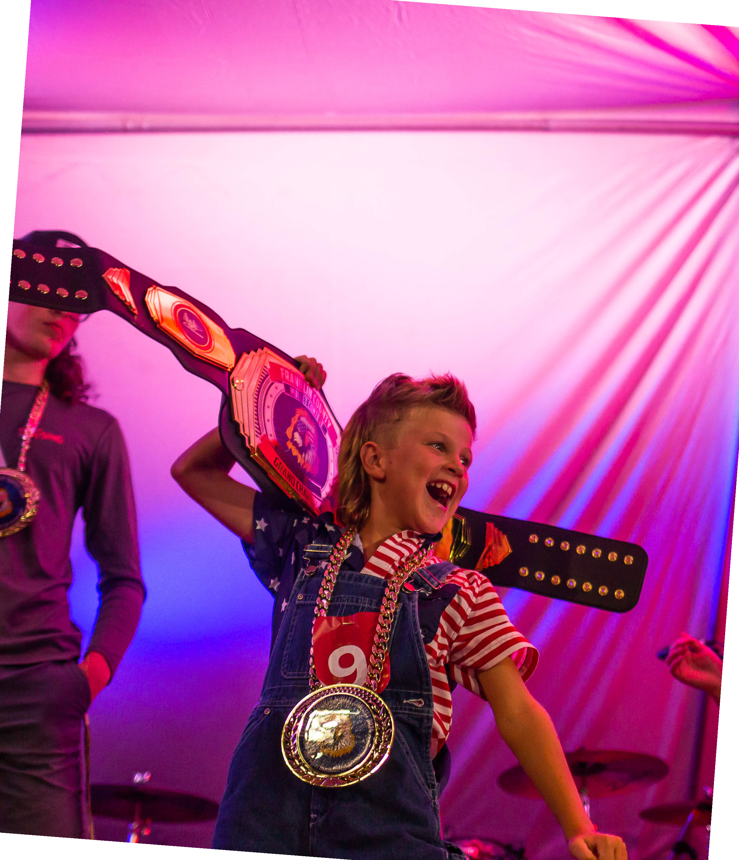 Kid holding the championship belt behind head and smiling at the crowd in excitment